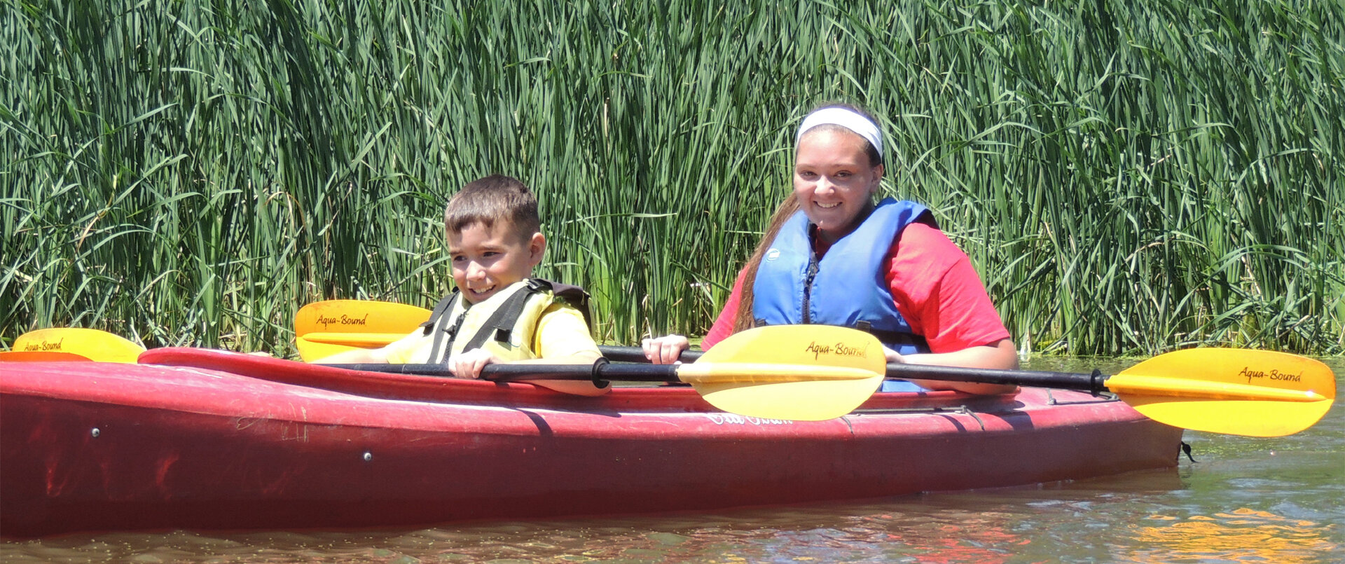 Two campers rowing in a kayak on the water.