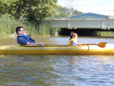 Two young campers kayaking in a yellow kayak.