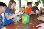 Campers and counselors painting container for totem pole craft