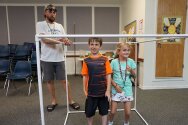 Two campers standing inside large PVC pipe cube