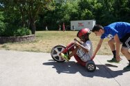 Camper trying out the tricycle with the help of his counselor