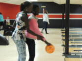 Counselors and campers working together to enjoy bowling.