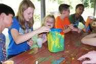 Campers and counselors painting container for totem pole craft