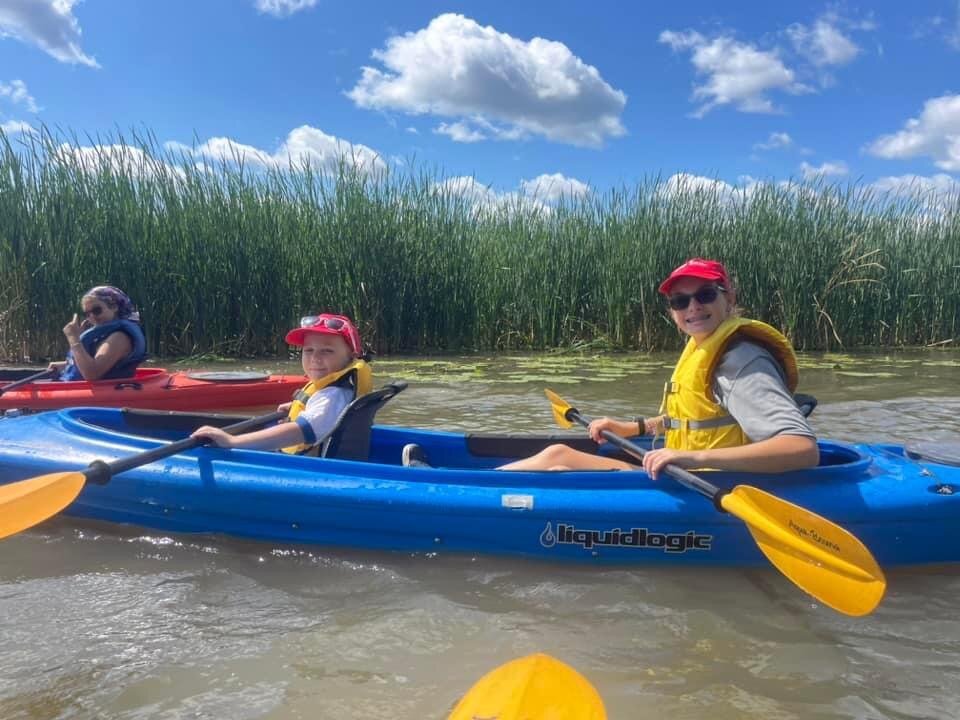 Two campers rowing in a kayak on the water.
