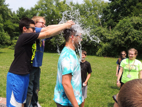 Campers breaking a water balloon over the head of a counselor.